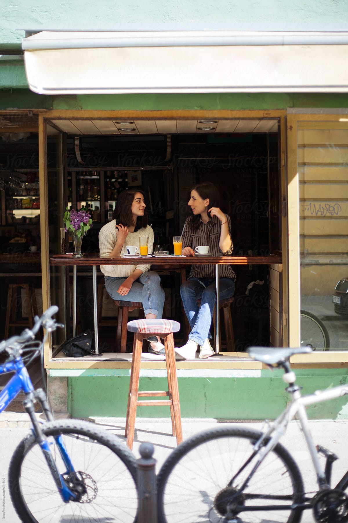 Two woman drinking coffee at the cafe during the sunny day