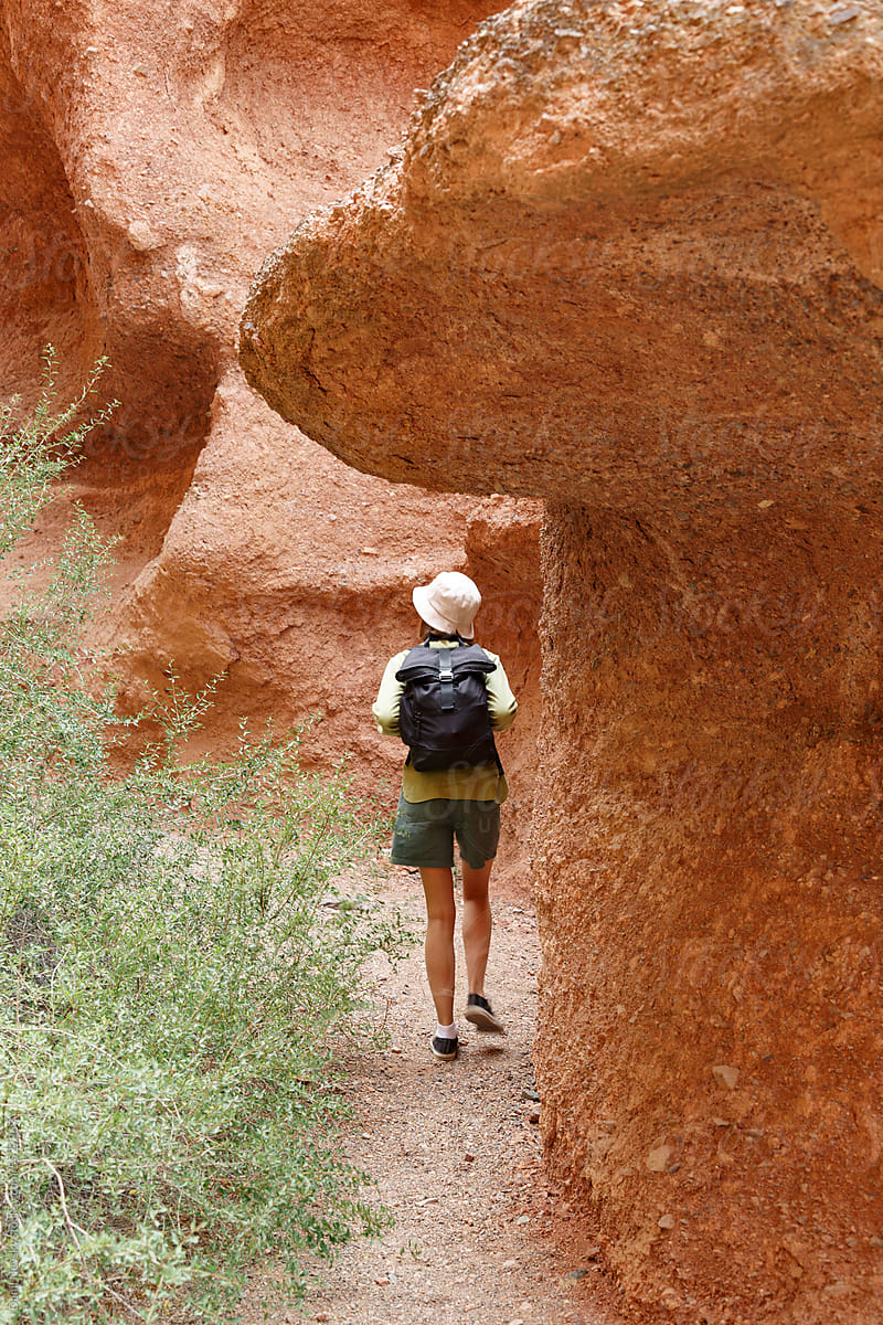 Traveler walking through red canyon tunnel