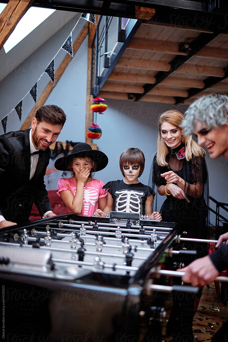 Halloween party at home. Happy family playing board football game