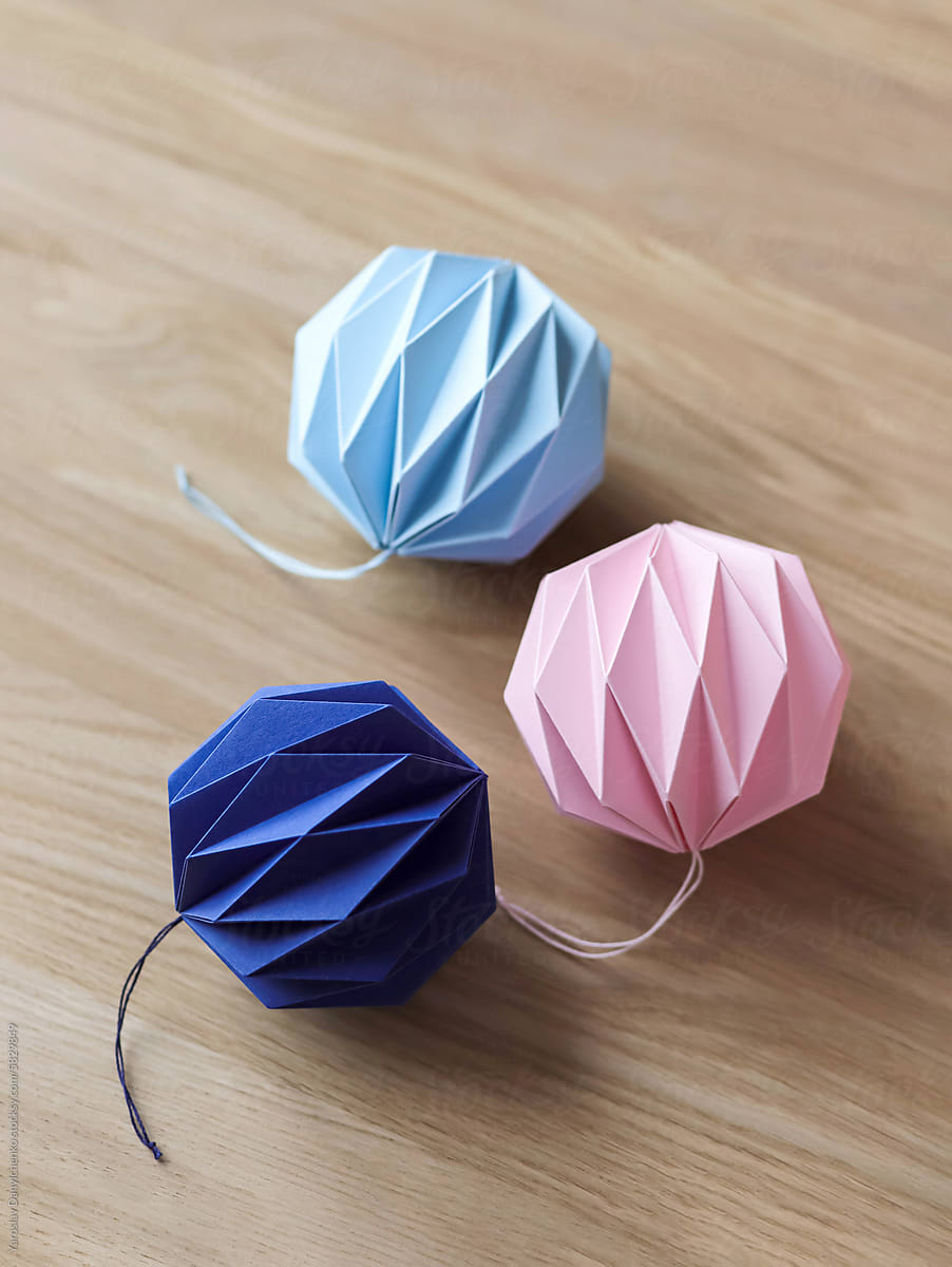 Three origami balls with attached laces laying on wooden surface