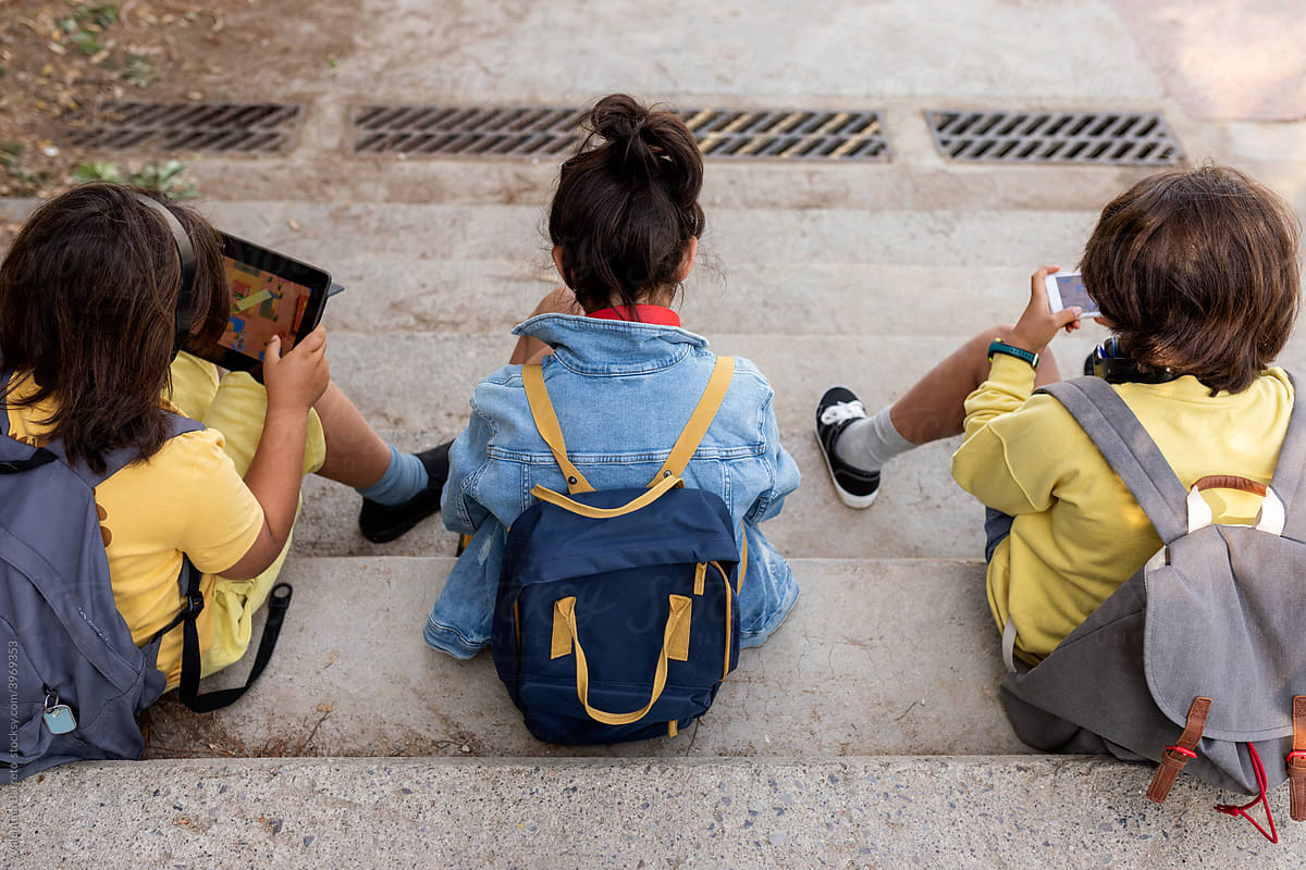 Kids sitting on the stairs using electronics