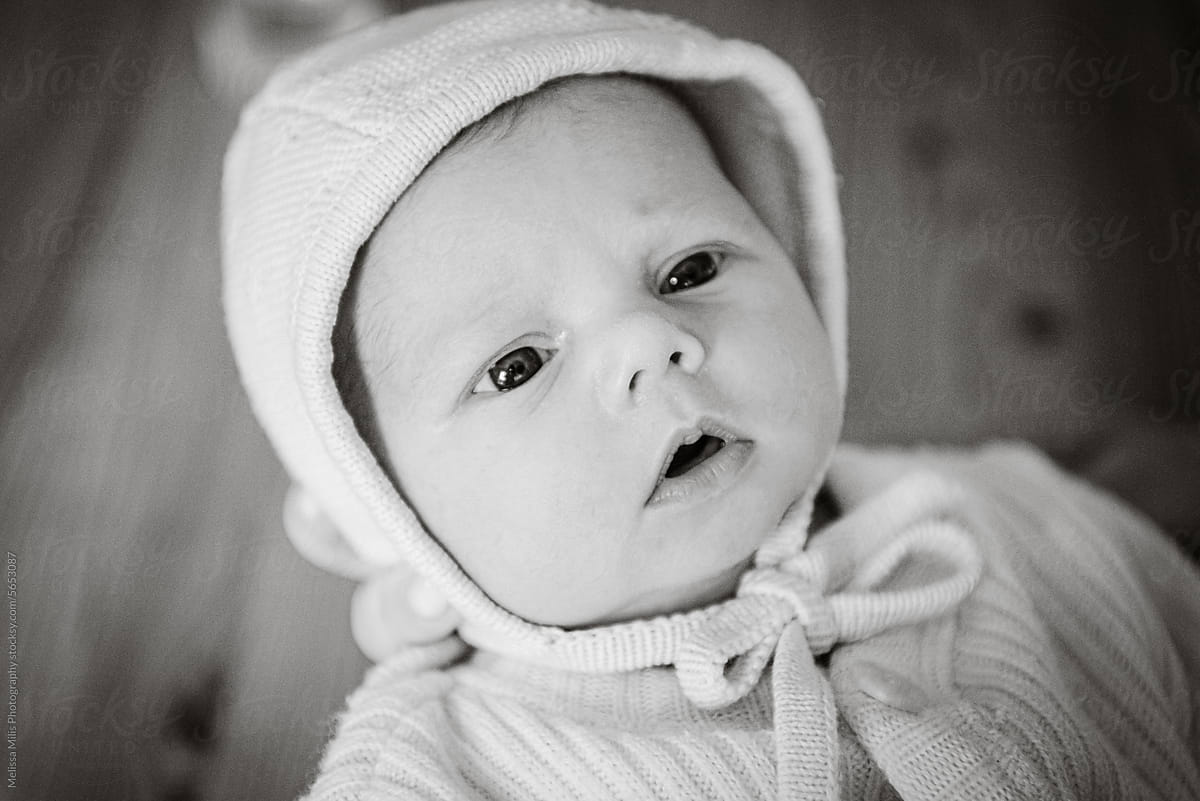 monochrome image of newborn with baby hat, eyes wide open