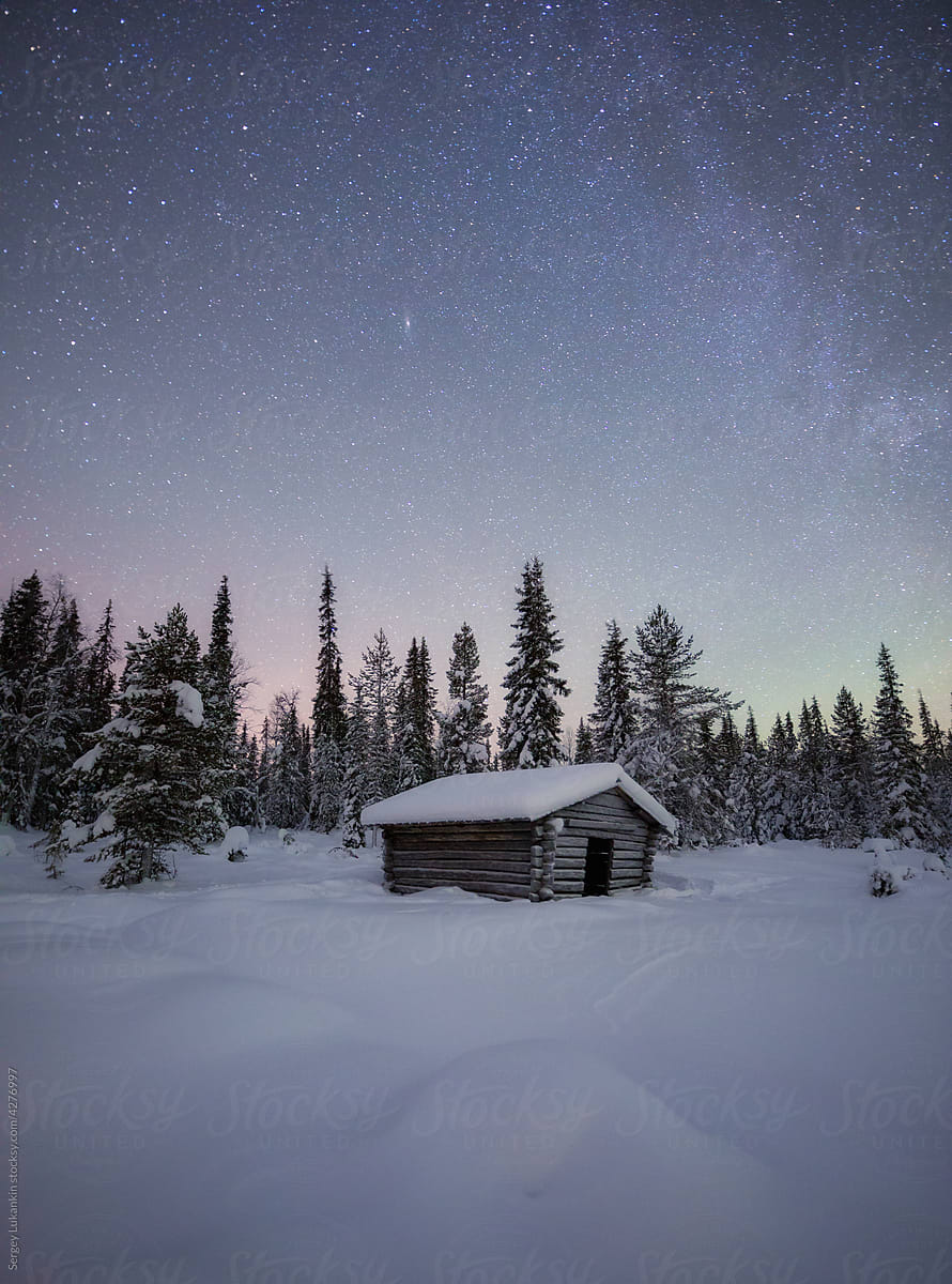 Snow-covered hut in winter under the starry sky