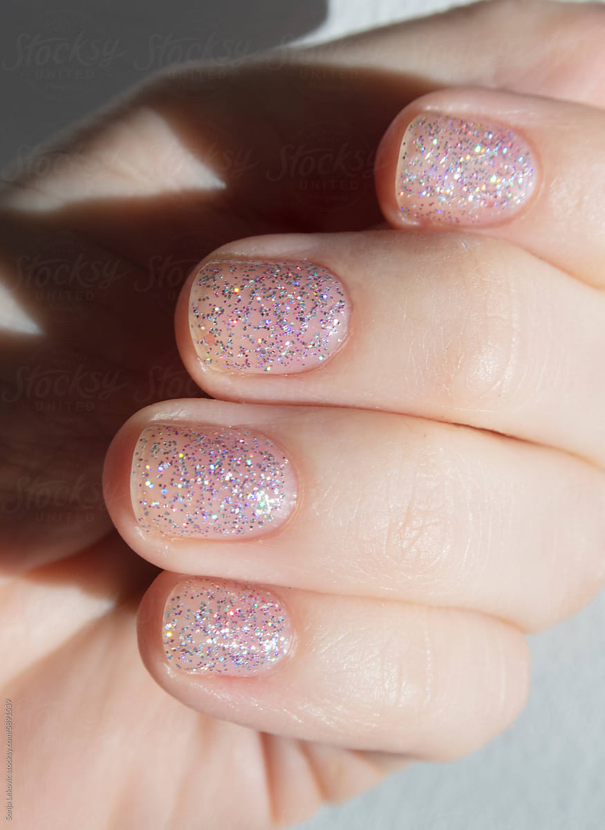 Transparent pink sparkling shiny nails closeup