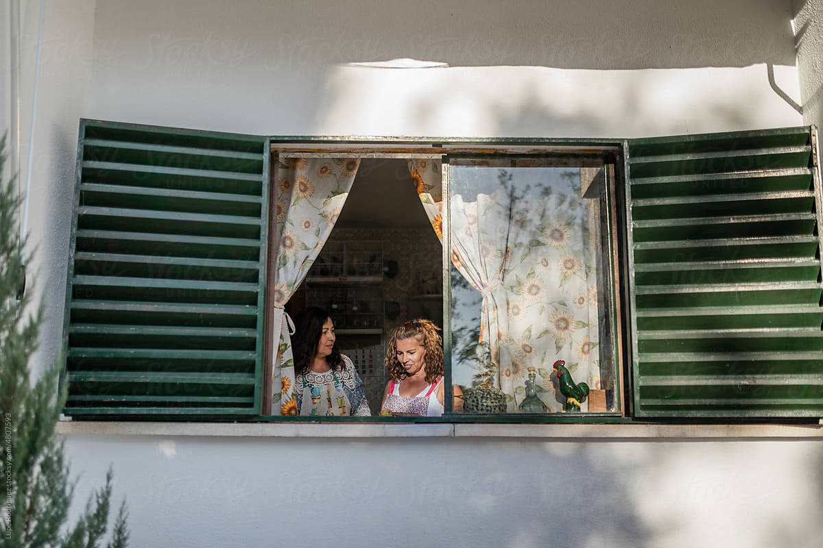 portrait through a window of two mature women cooking
