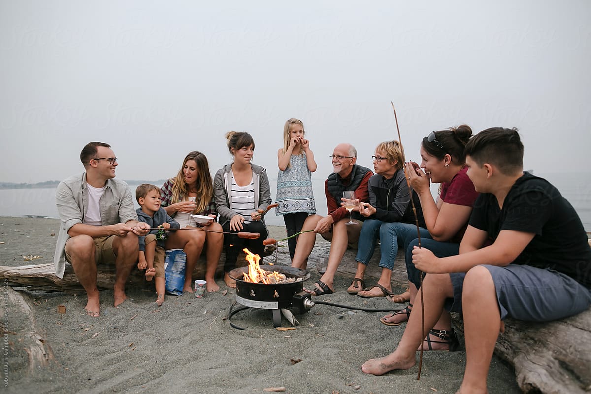 Multi generational family hanging out together around fire on the beach
