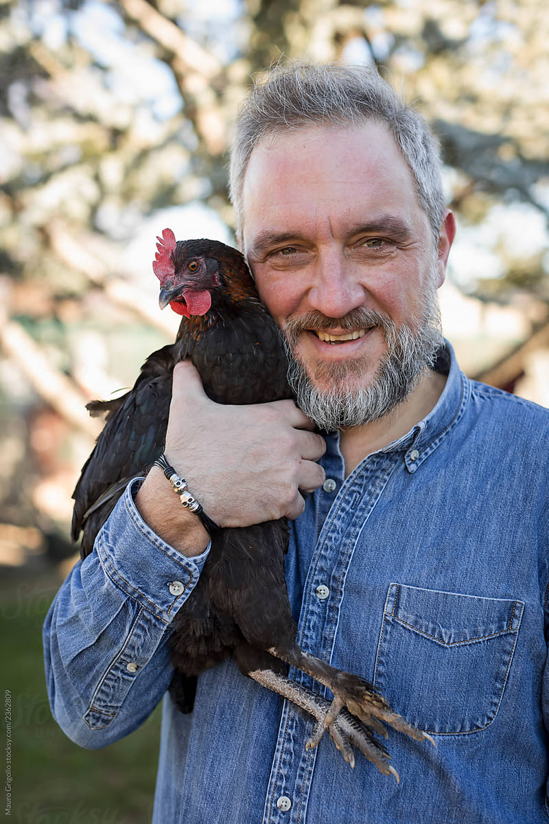 Adult Man holding a chicken.