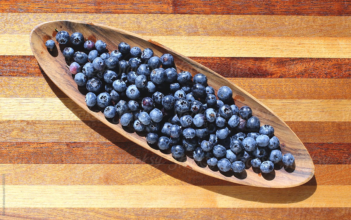 Tray with blueberries on wooden table.