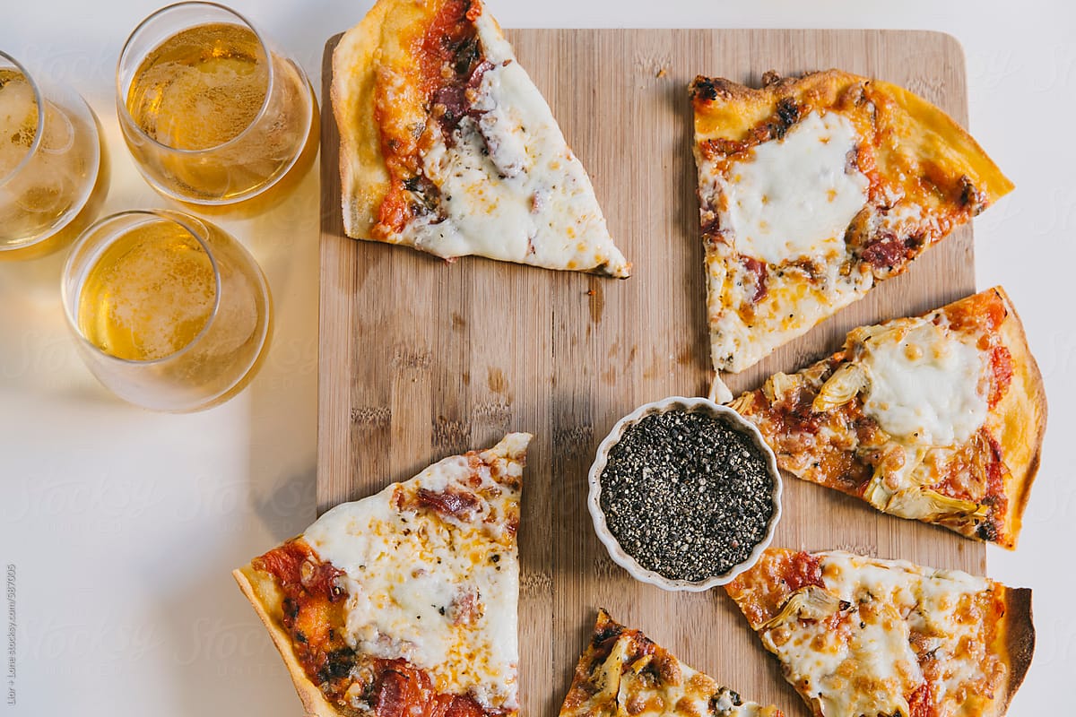 Slices of pizza on cutting board and glasses with beer