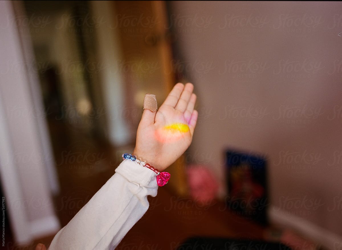 child catches rainbow prism light in palm