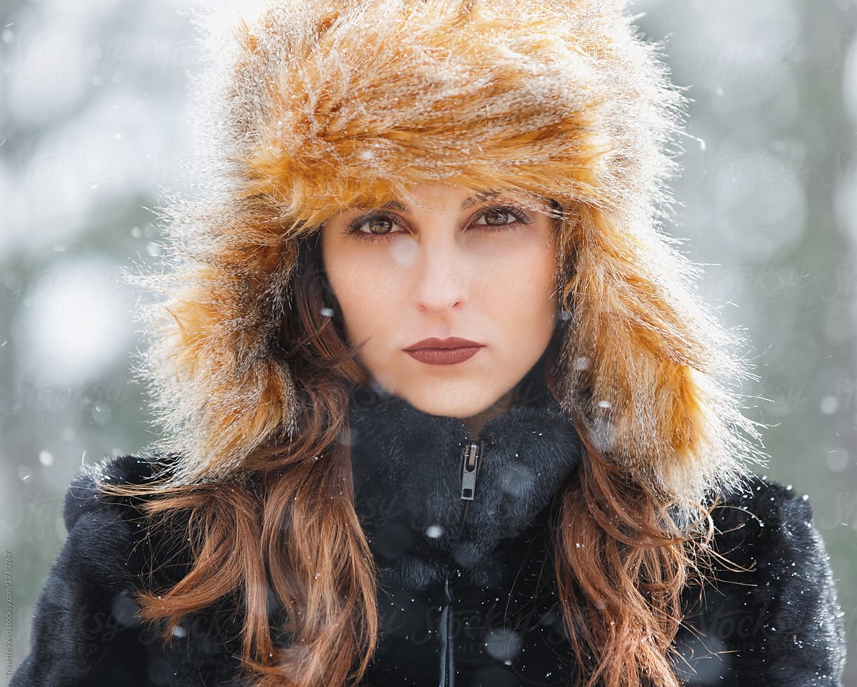 Portrait of woman standing on balcony of ski lodge with snow falling around her in winter