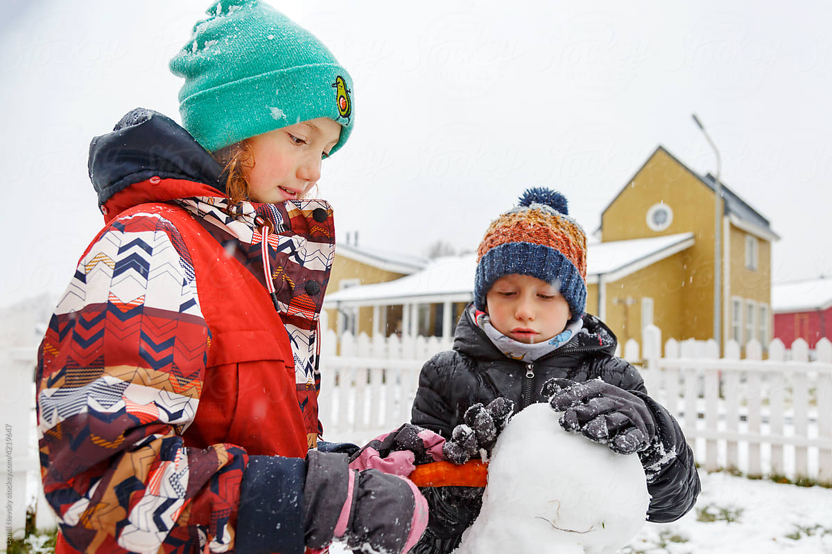 Cute children building snowman in winter