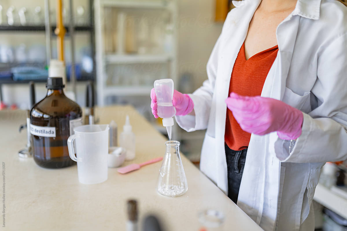 Crop chemist pouring liquid solution in flask in laboratory