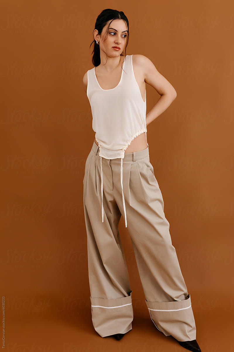 Stylish female model standing in studio against brown background