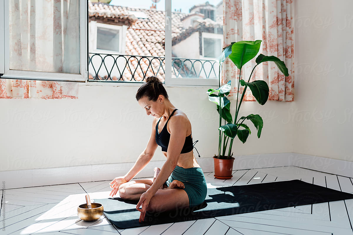 Relaxed woman meditating in lotus pose with singing bowl