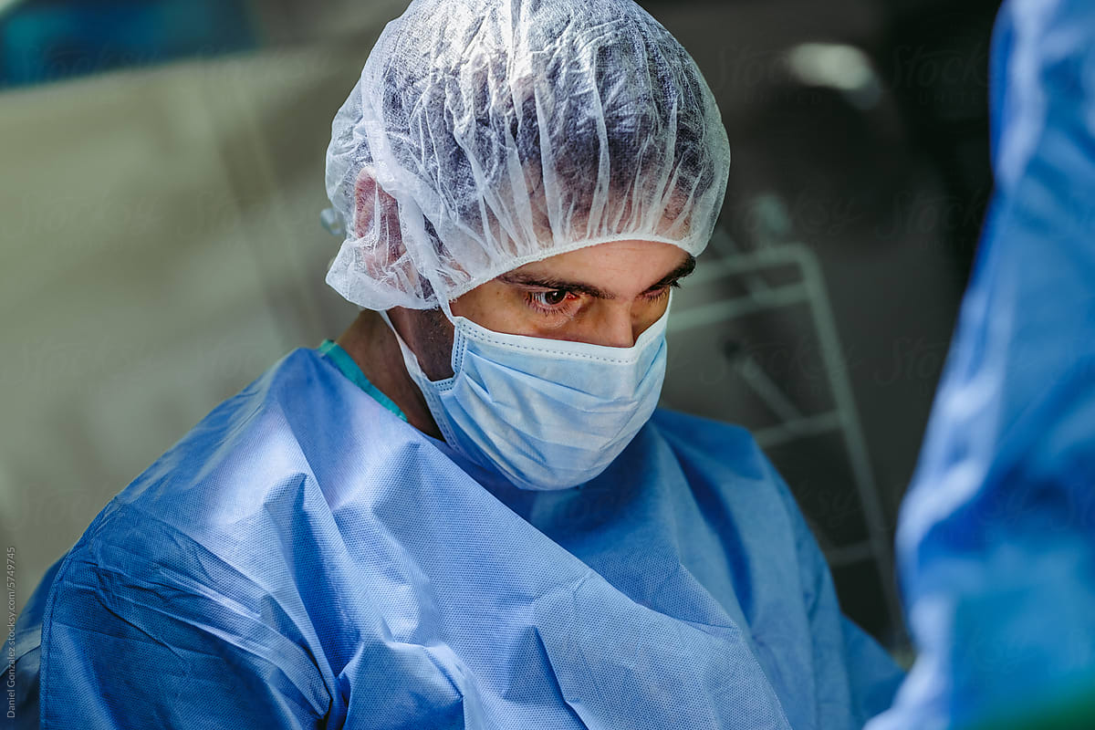 Serious veterinary doctor in mask standing while performing surgical o