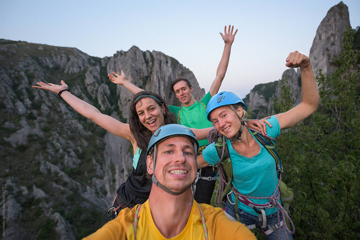 Lively rock climbers celebrating ascension on top of the mountain