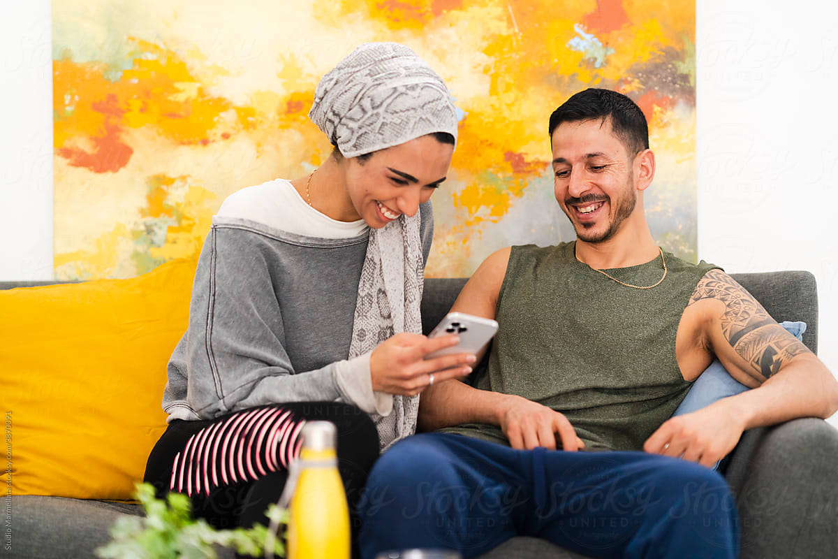 Cheerful Muslim couple looking at smartphone