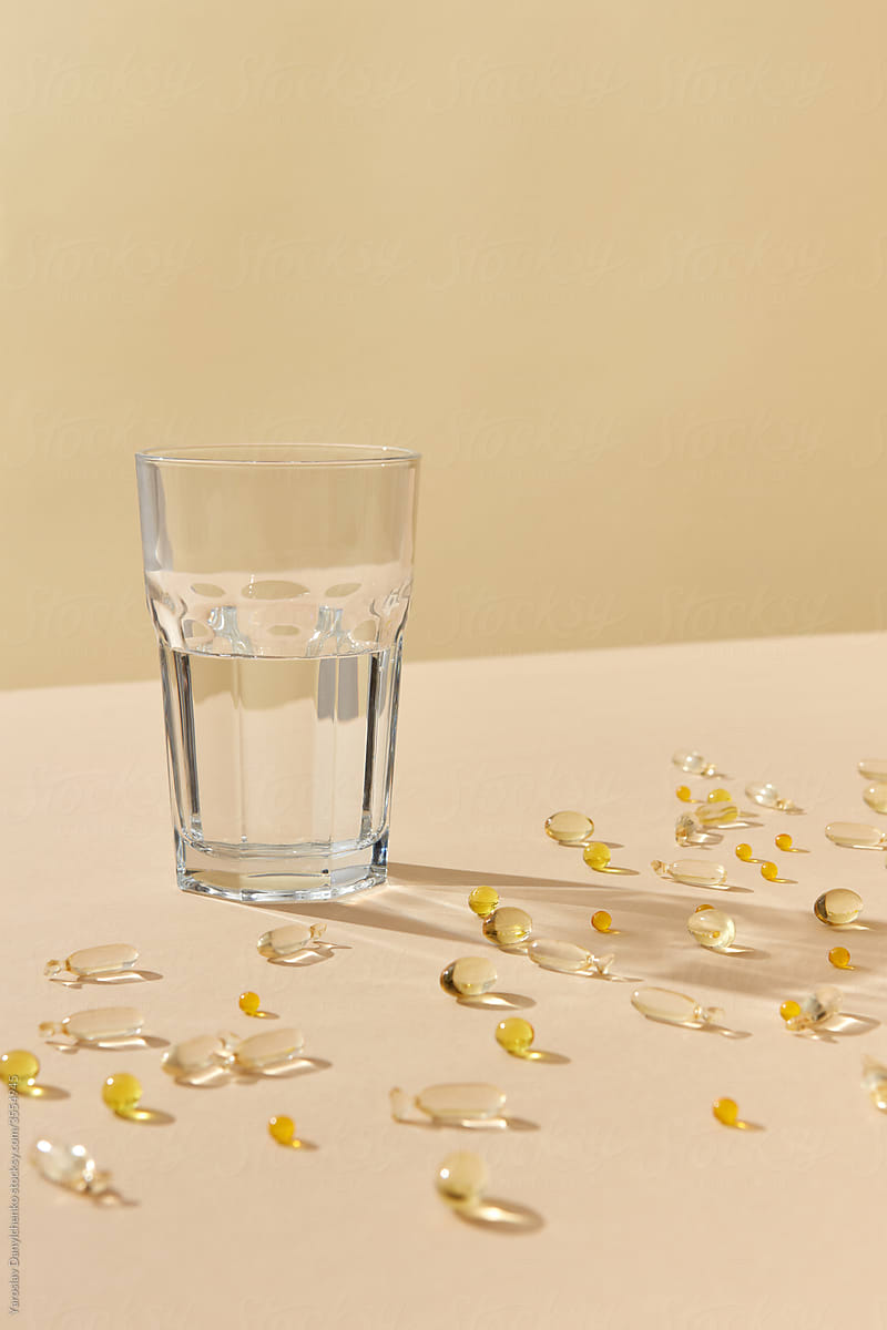 Transparent glass of water with medical drug capsules.