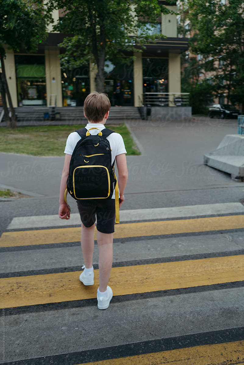Unrecognizable pupil with backpack goes to school.