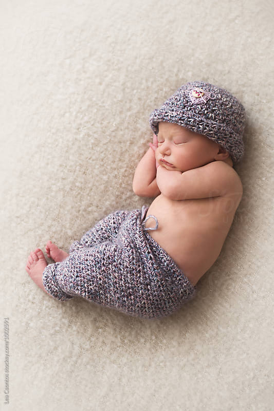 Adorable sleeping newborn baby wearing a knit hat and trousers