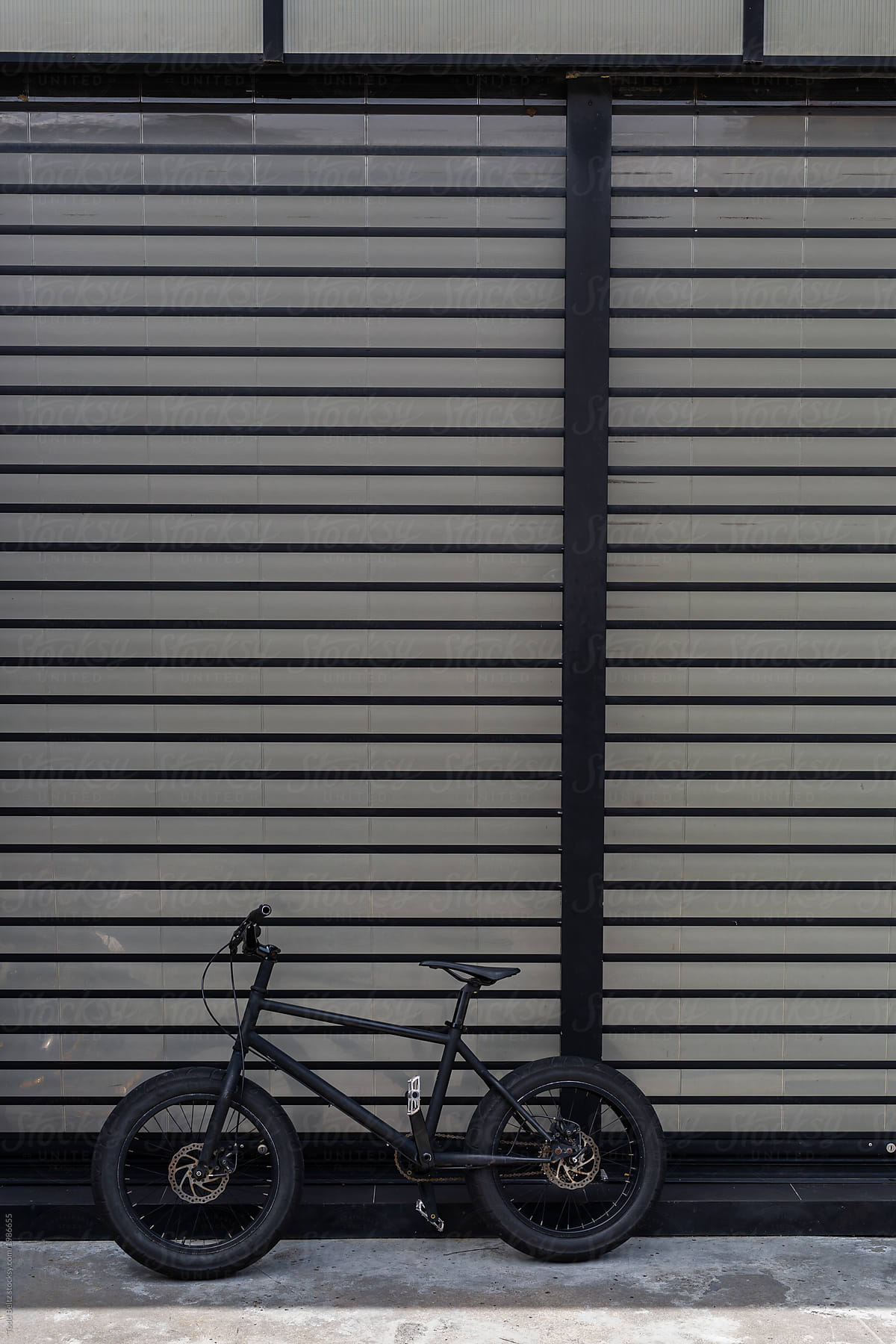 A black bike leans against a black building