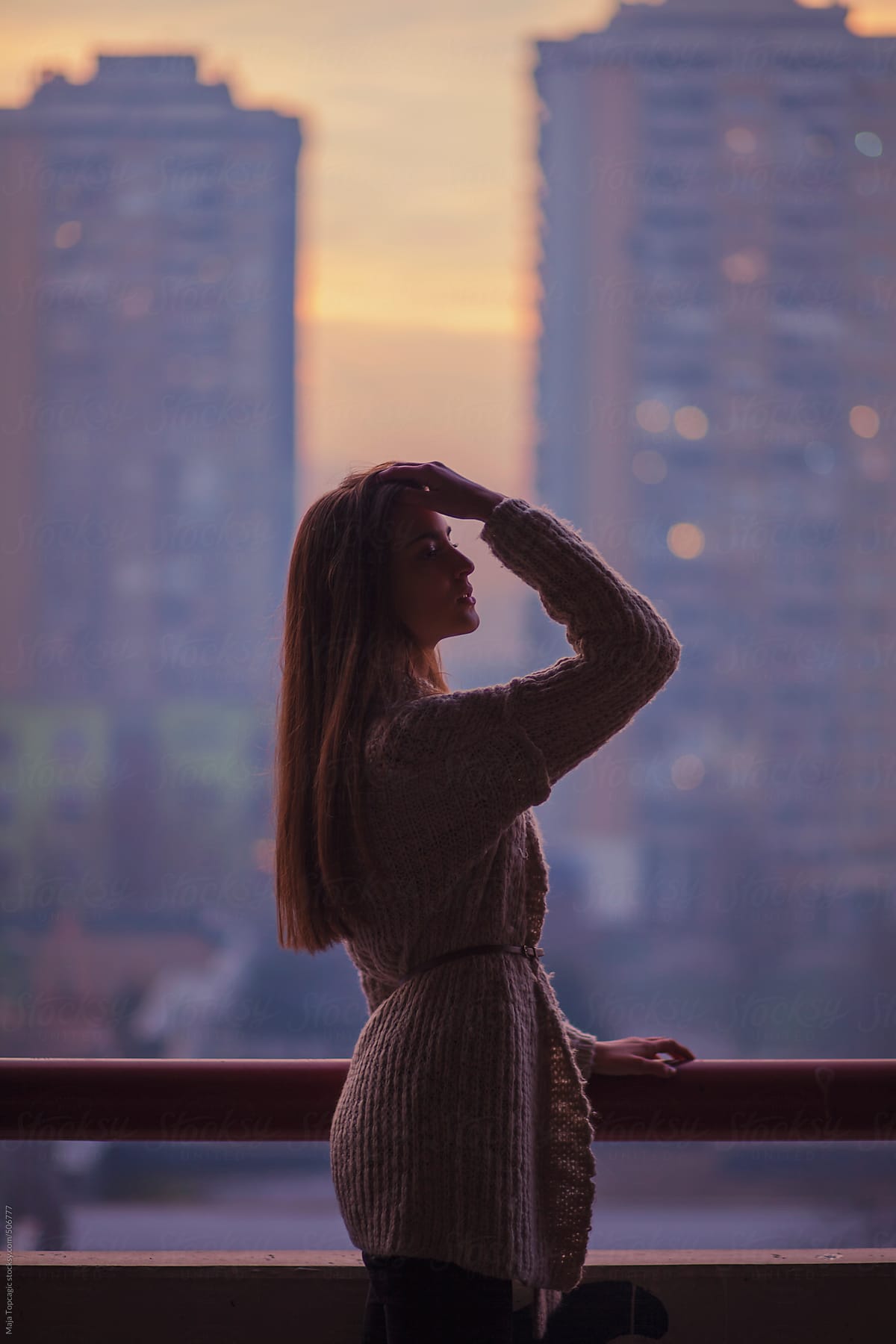 Young beautiful woman with blue eyes and long brown hair outside the city at sunset