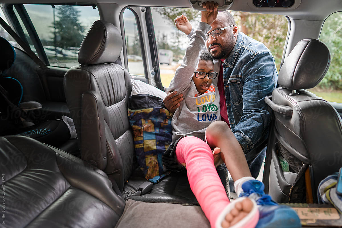 Father helps son with broken leg into vehicle