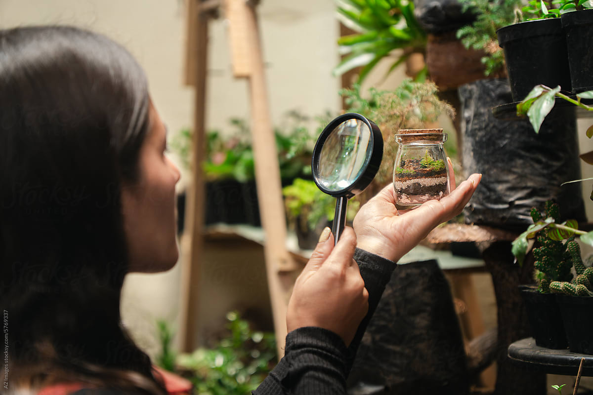 Woman observing a terrarium with a magnifying glass