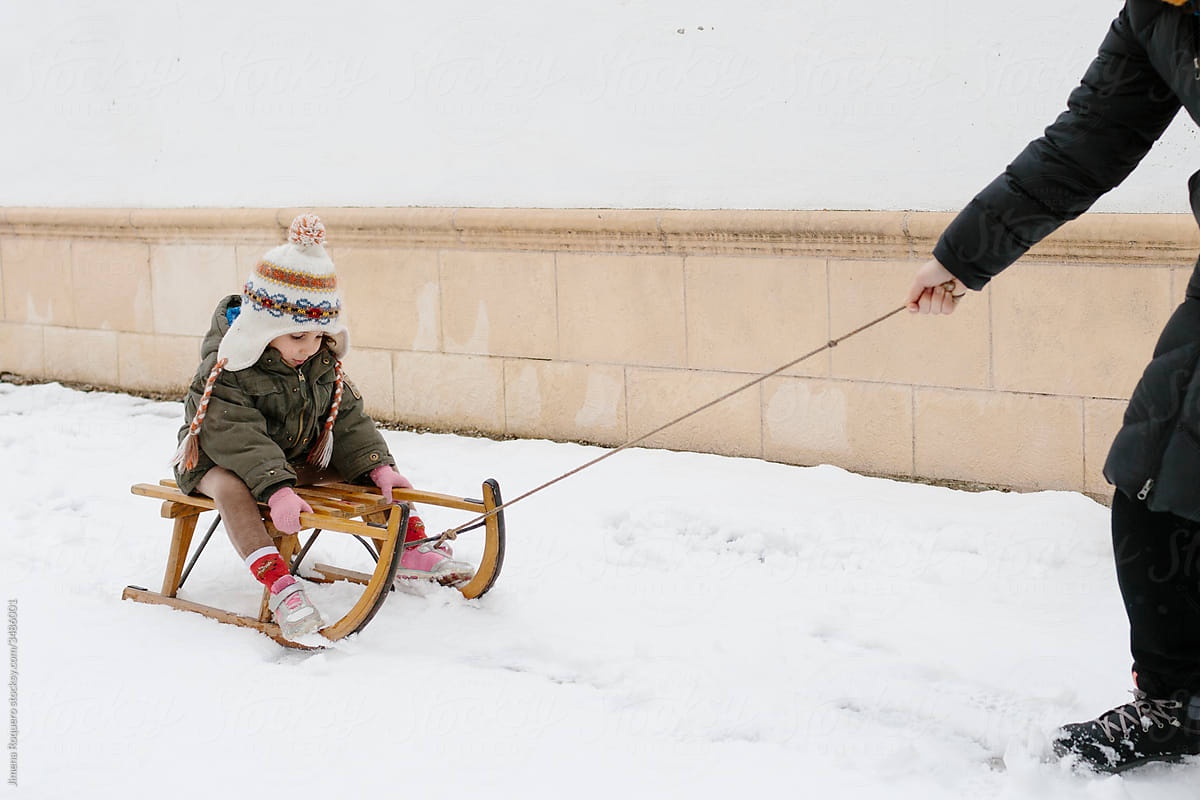 Kid riding a sleigh pulled by an anonymous arm
