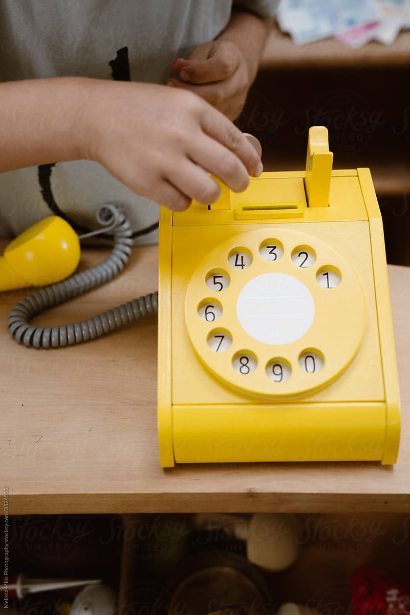 little boy playing with a bright yellow wooden phone