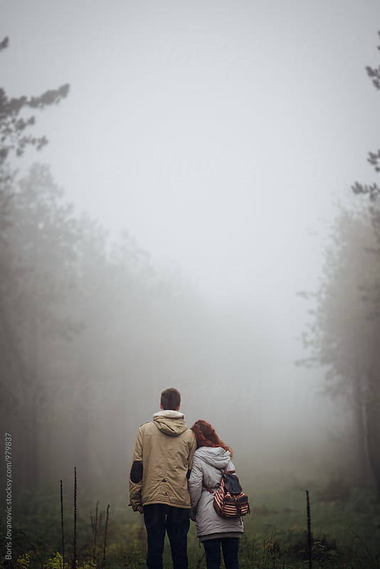 Back portrait of couple standing in the middle of forest