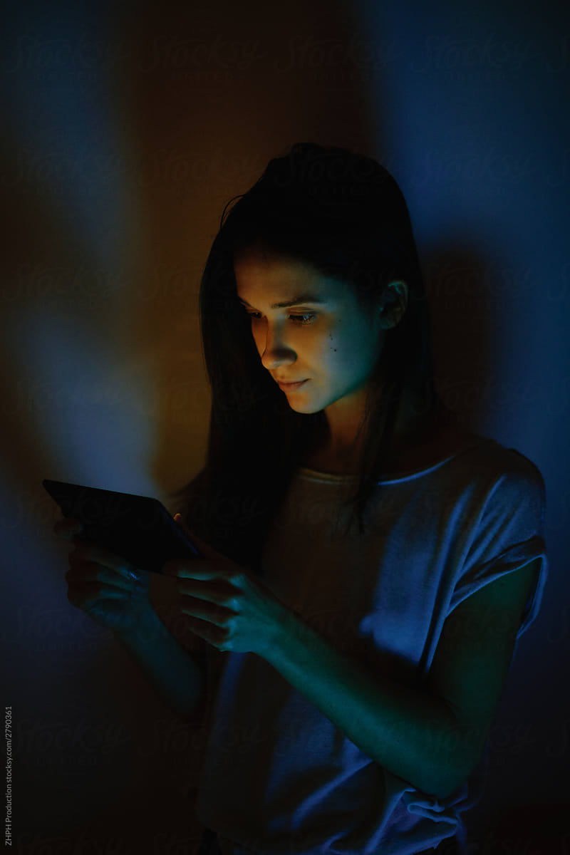 Young woman lit with tablet screen light