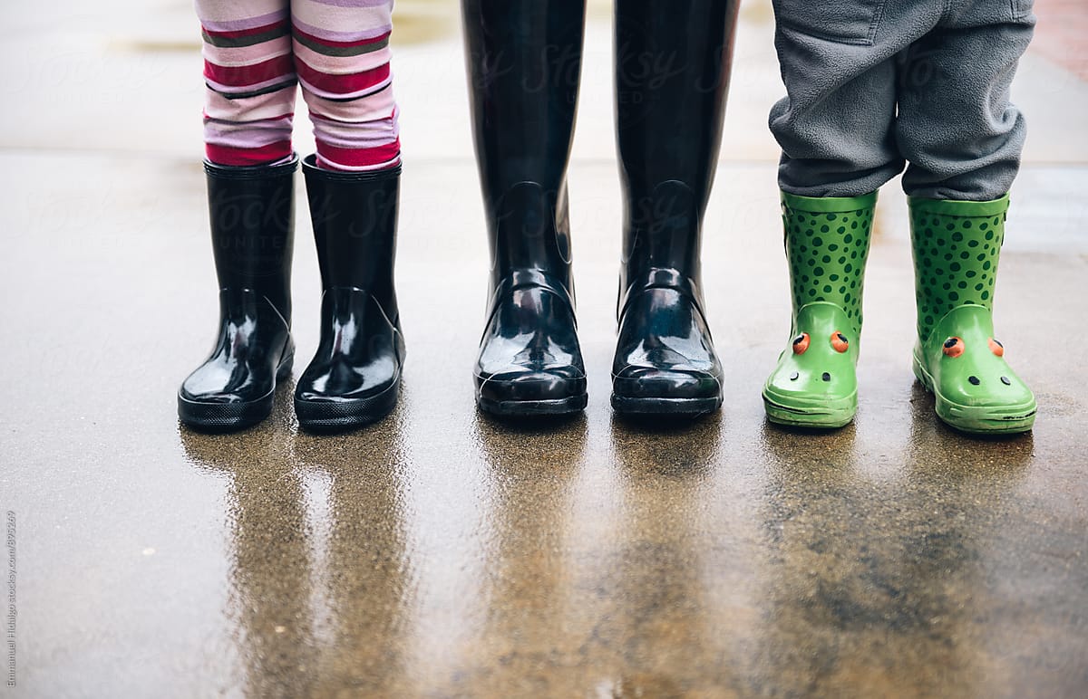 Just rain boots of mother, daughter and son standing outside