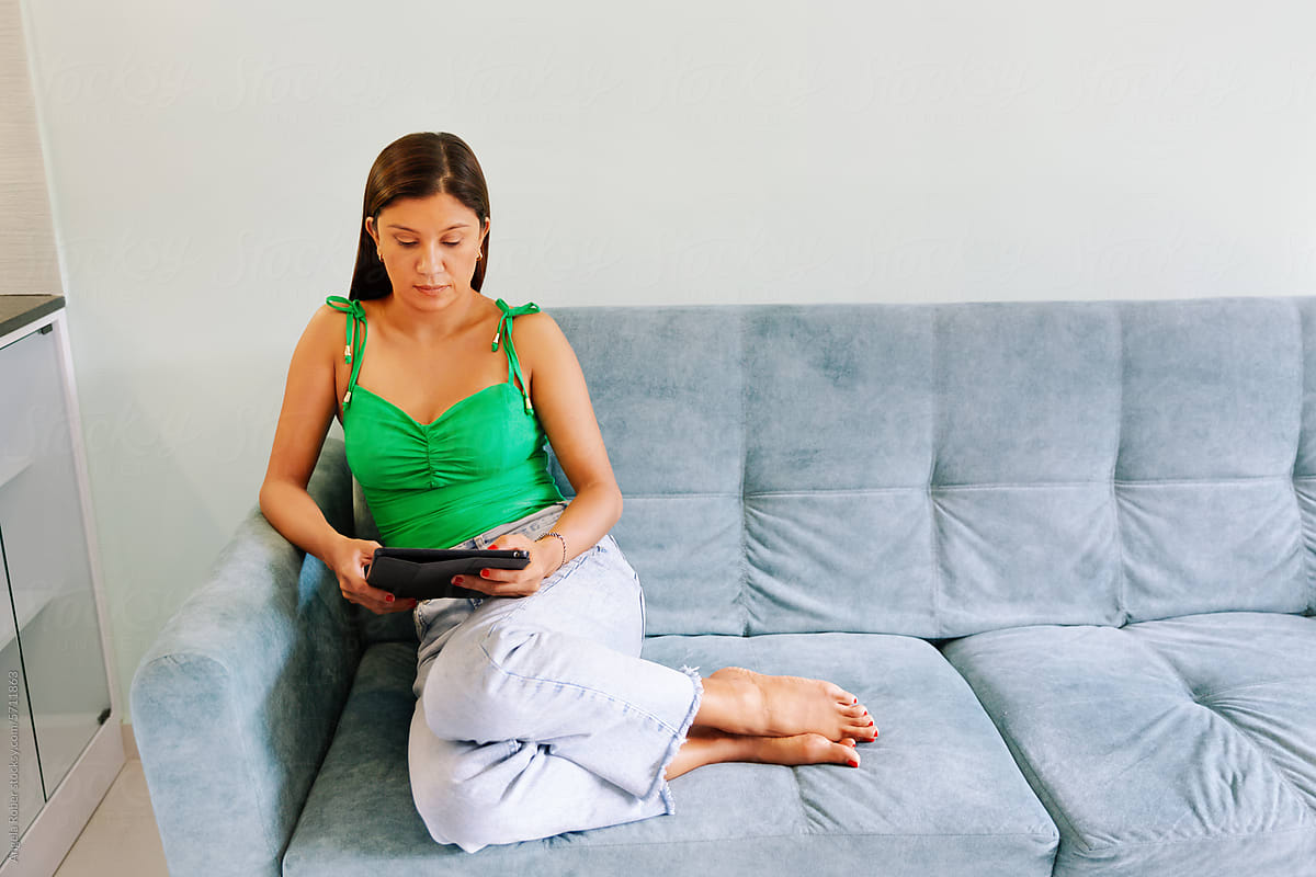 Woman resting on the sofa and looking at her tablet