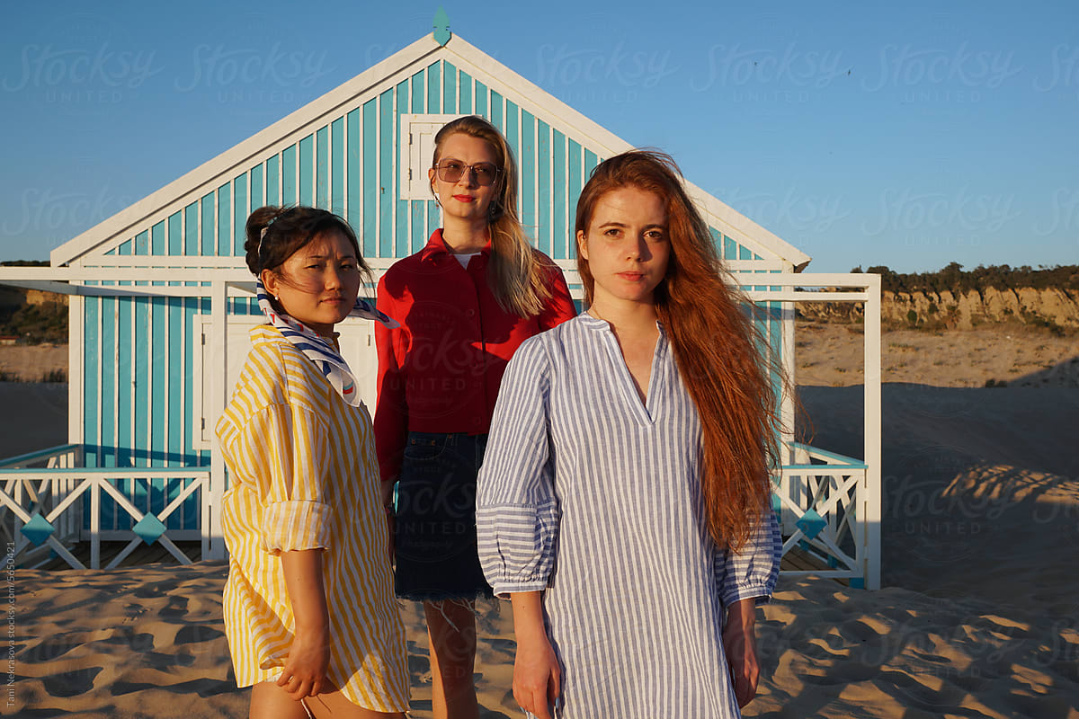 Three young females standing together by the ocean. Feminism
