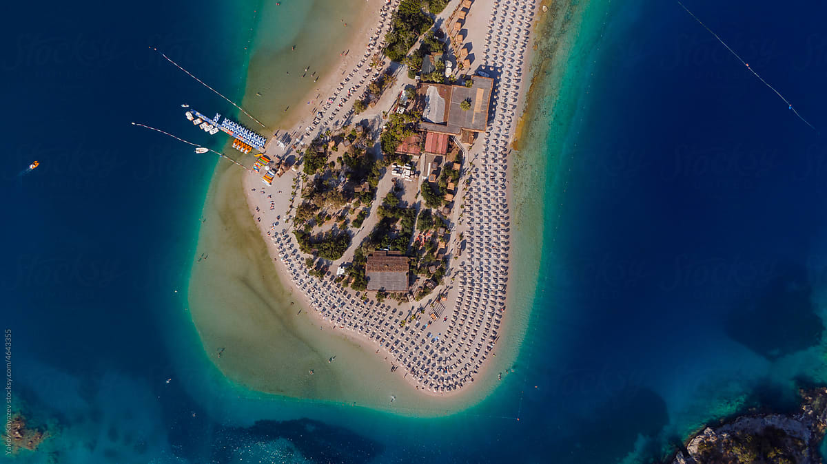 aerial view of a beach at peninsula - azure water and many chairs