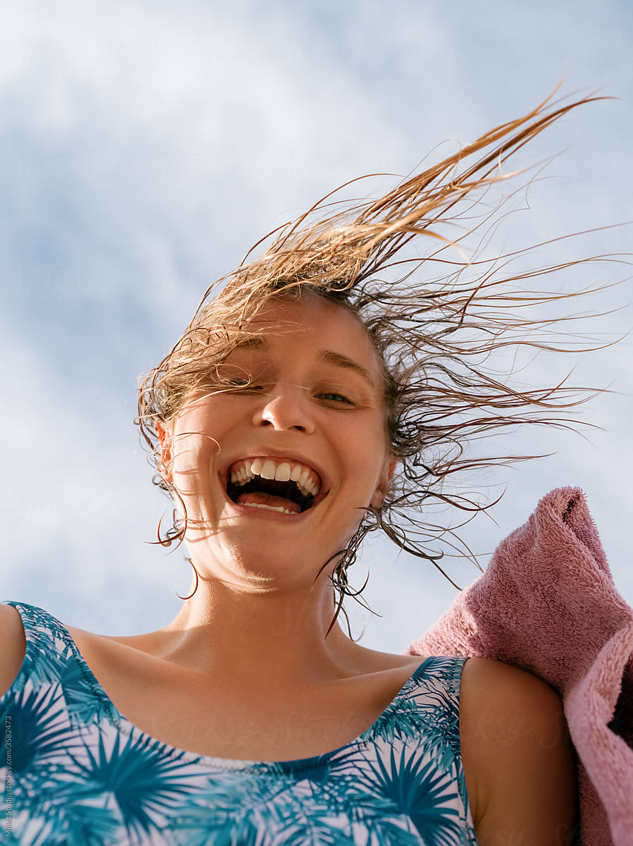 Excited woman with towel resting against cloudy sky