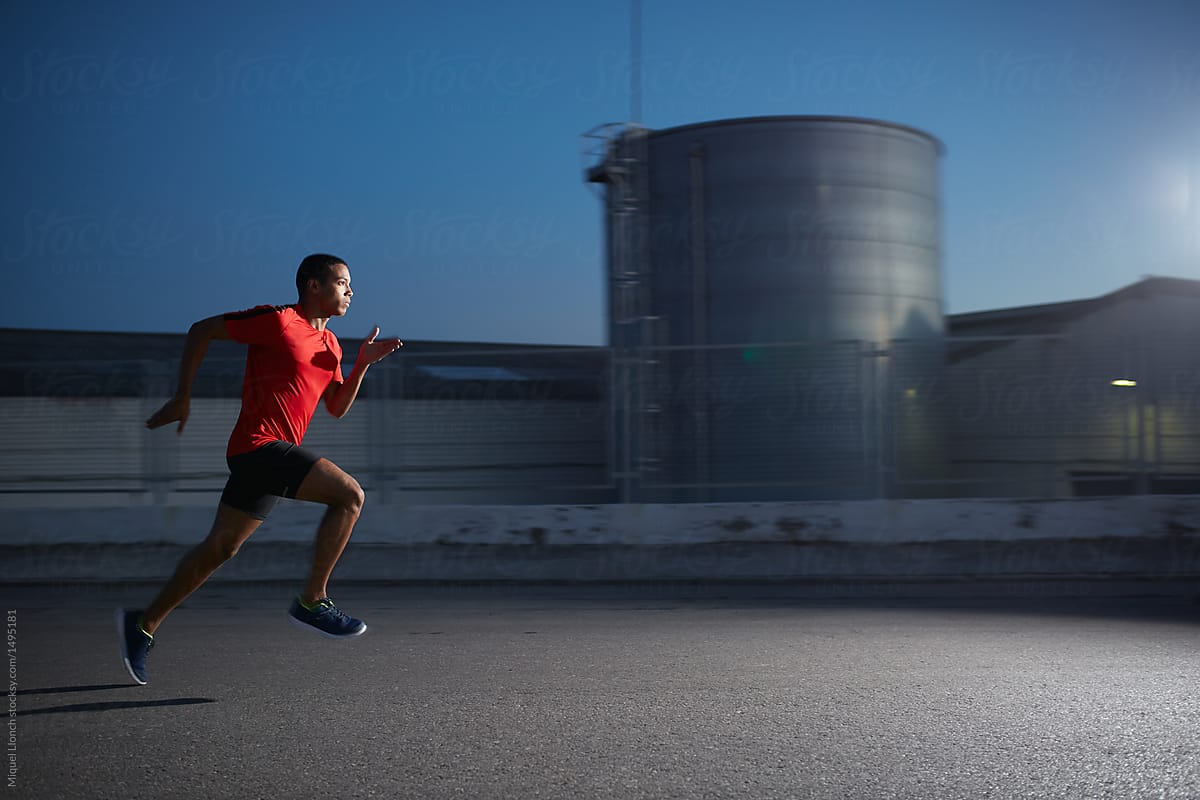 Action photo of a runner in industrial area at night