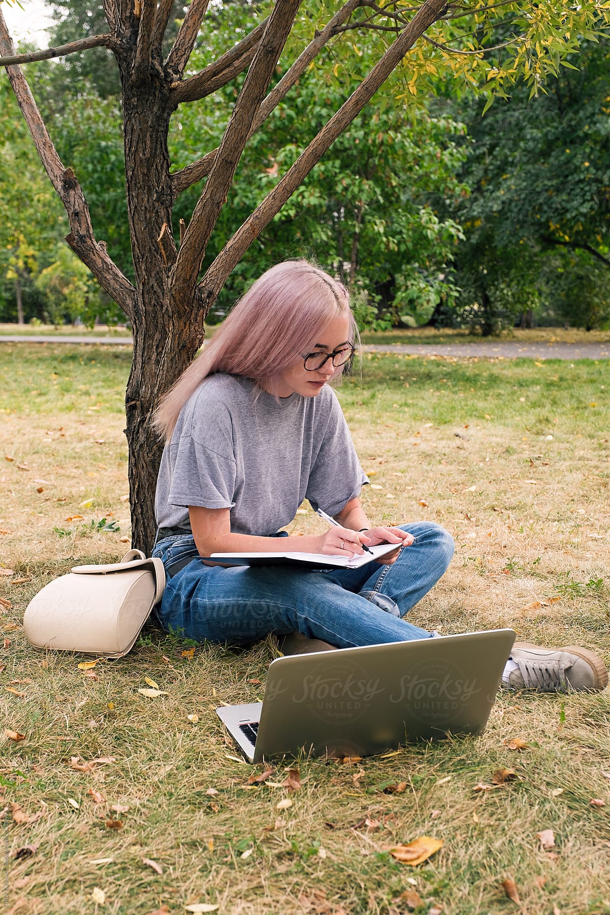 Busy pink-haired woman writing notes in park