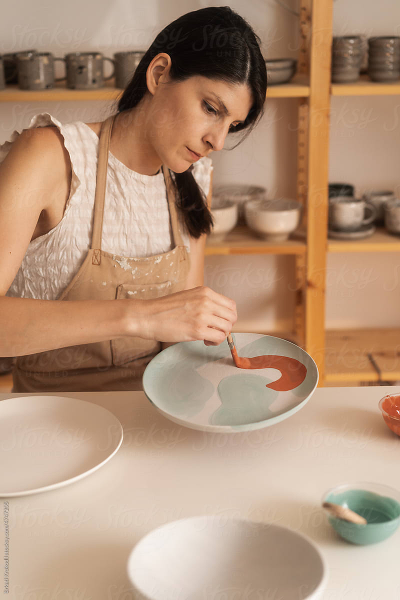 Woman Doing Brush-On Glaze Technique On The Pottery