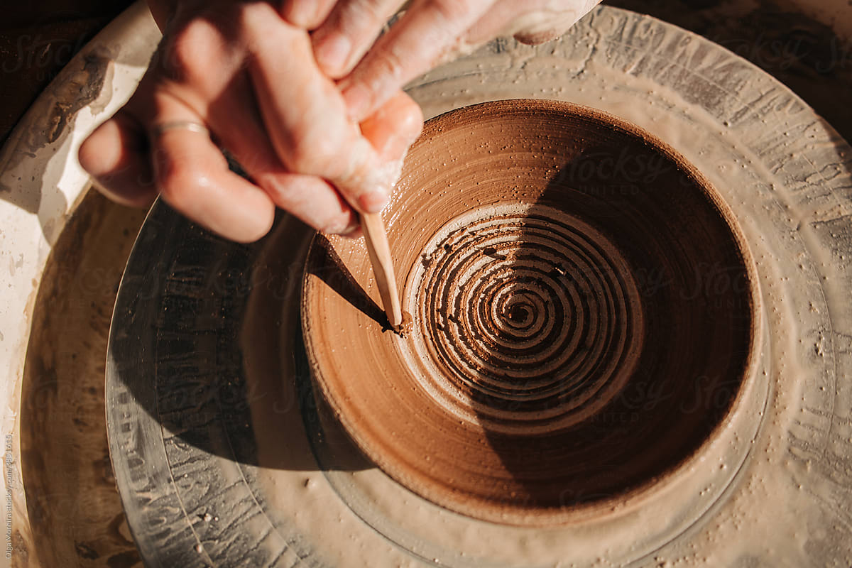 Female hands decorating a plate on a pottery wheel