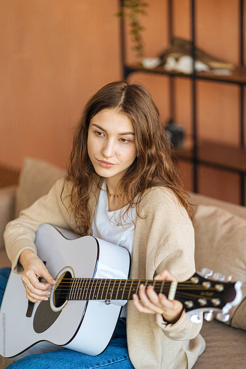 young woman playing guitar at home