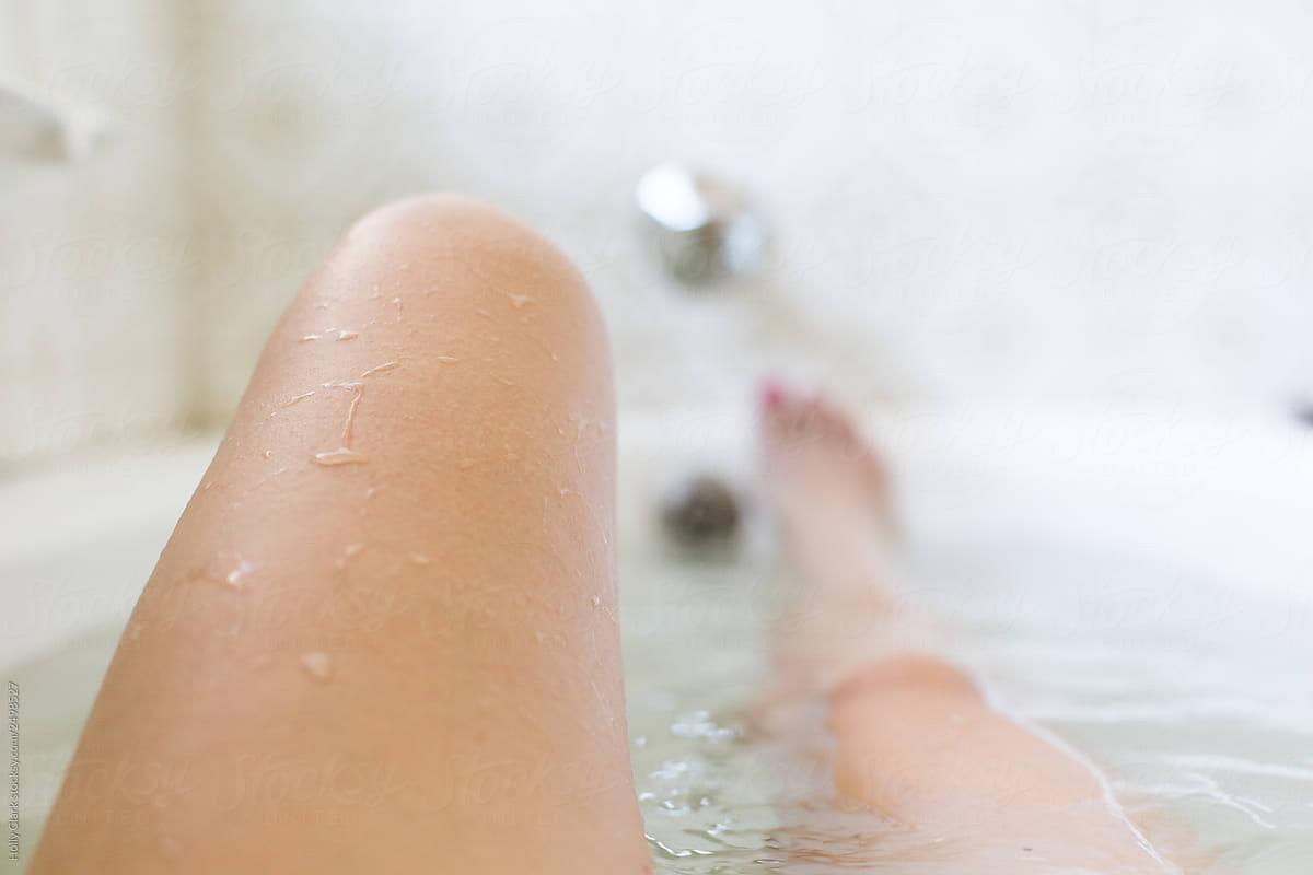 Woman\'s raised knee relaxing in hot, relaxing bathtub