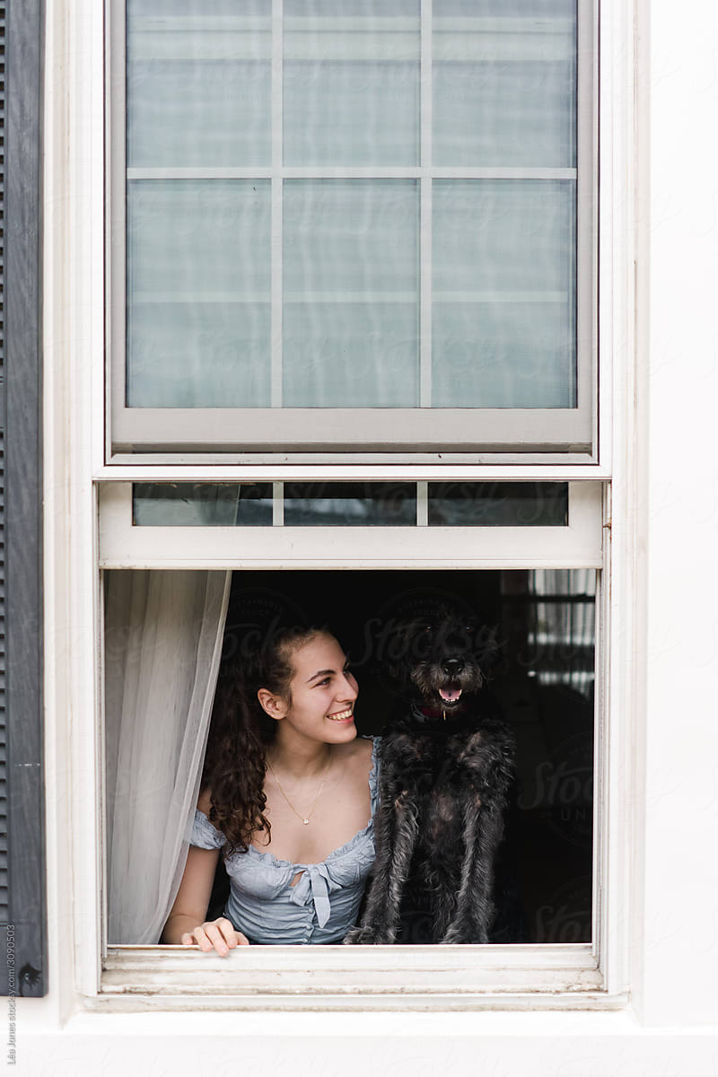 young woman  and dog looking out through the window