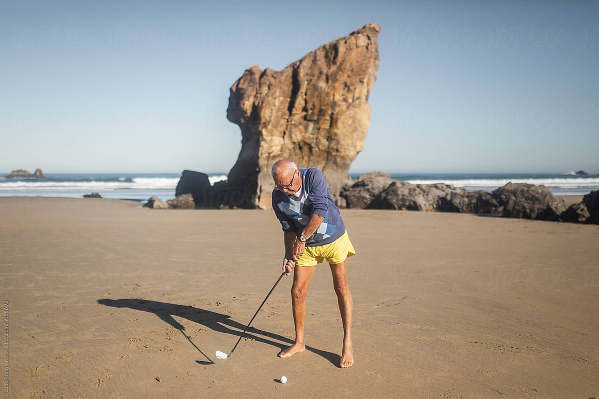 senior man playing golf on the beach