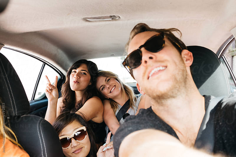 three girls and one guy in car on road trip having fun