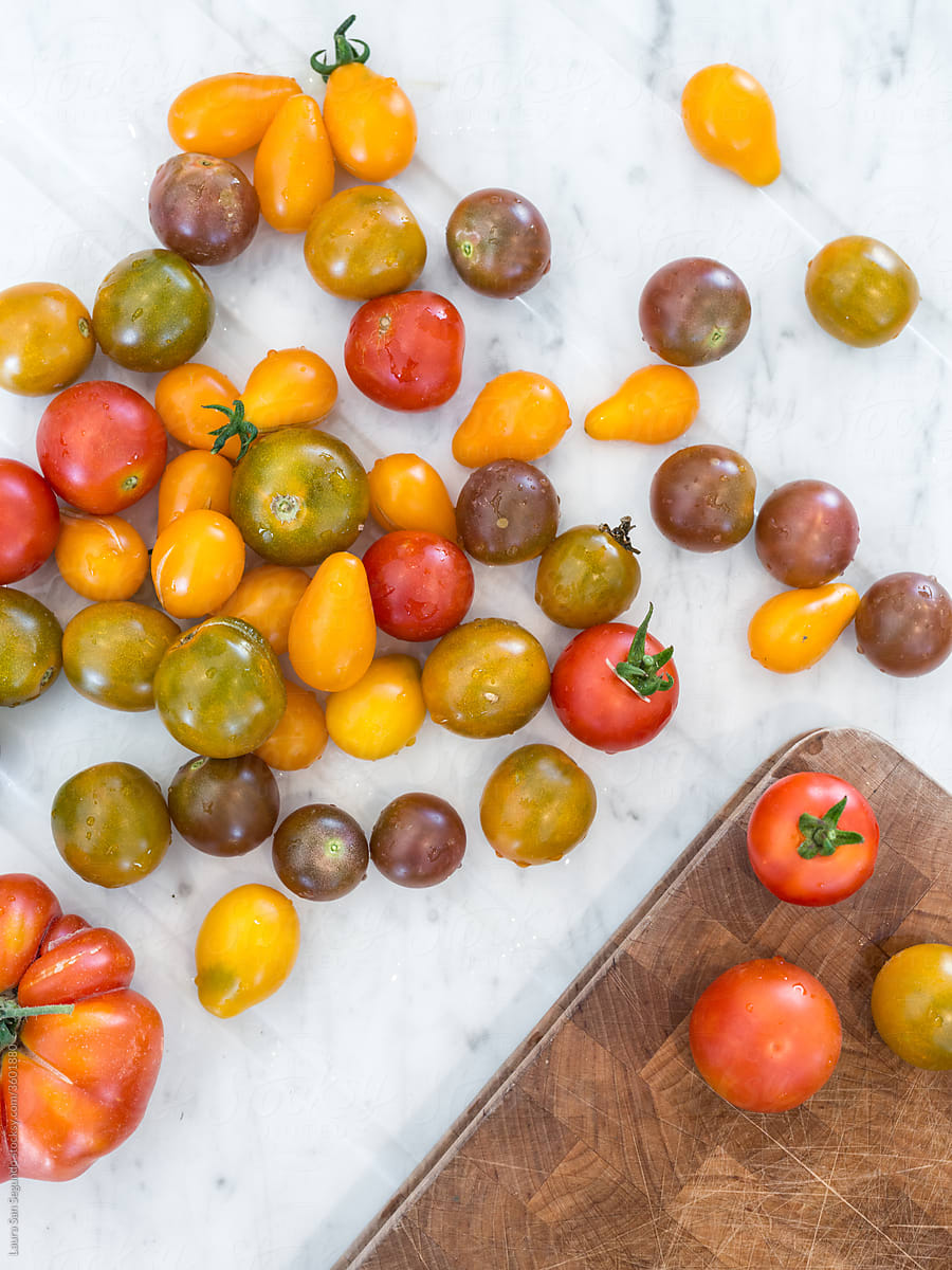 Mixed cherry tomato on white marble table with a wood chopping board