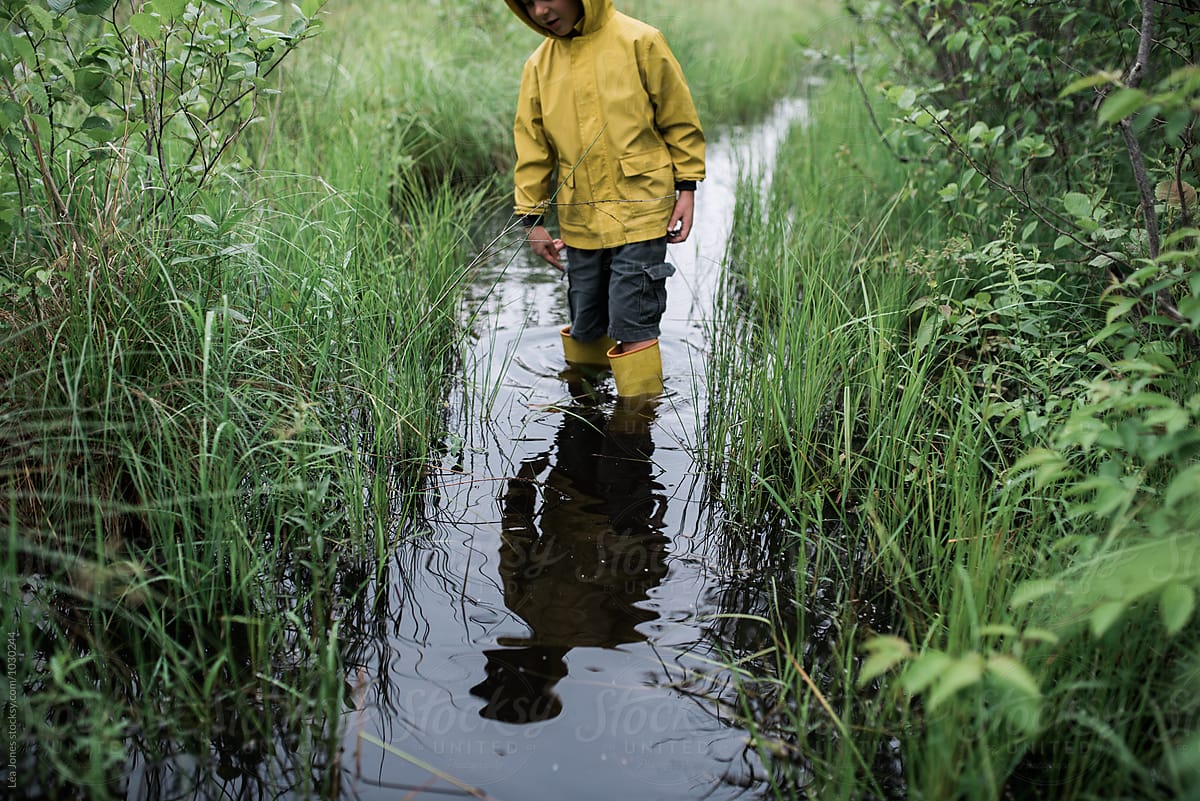 stock photo of little boy on walk in a flooded path