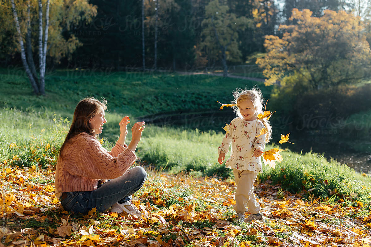 Mother and daughter playing with autumn leaves